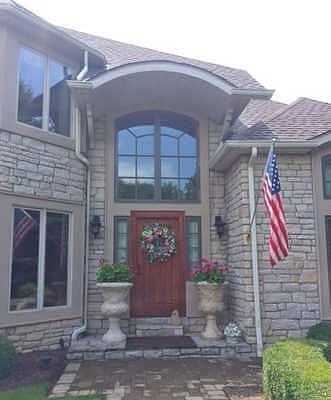 Stone home entryway with large window curved at top
