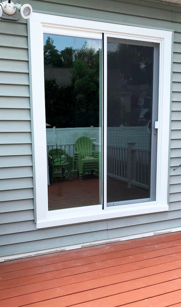 Replacement vinyl sliding patio door on a home with gray siding
