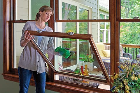 Woman cleaning double-hung windows with cloth