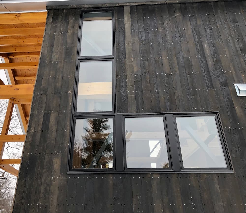 Exterior view of cabin with black-clad wood windows