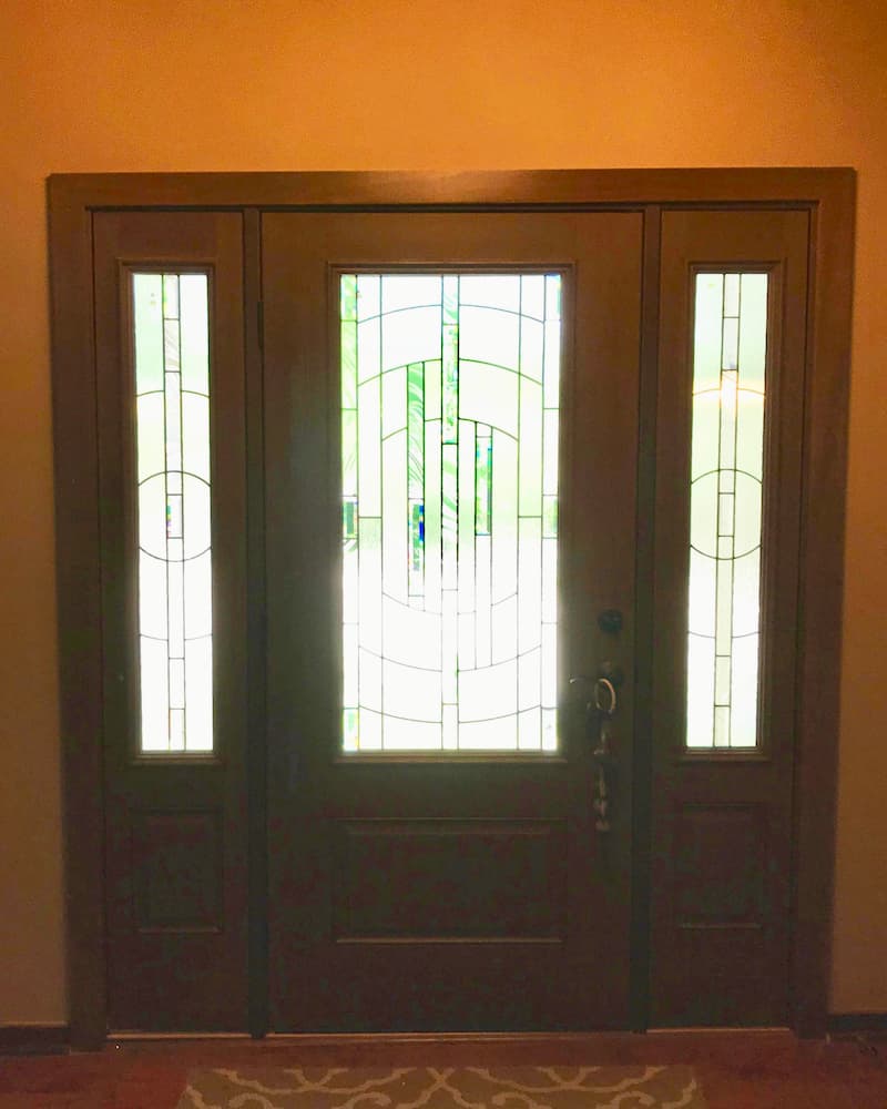 Interior view of new wood-look fiberglass entry door with 3/4 sidelights and decorative glass