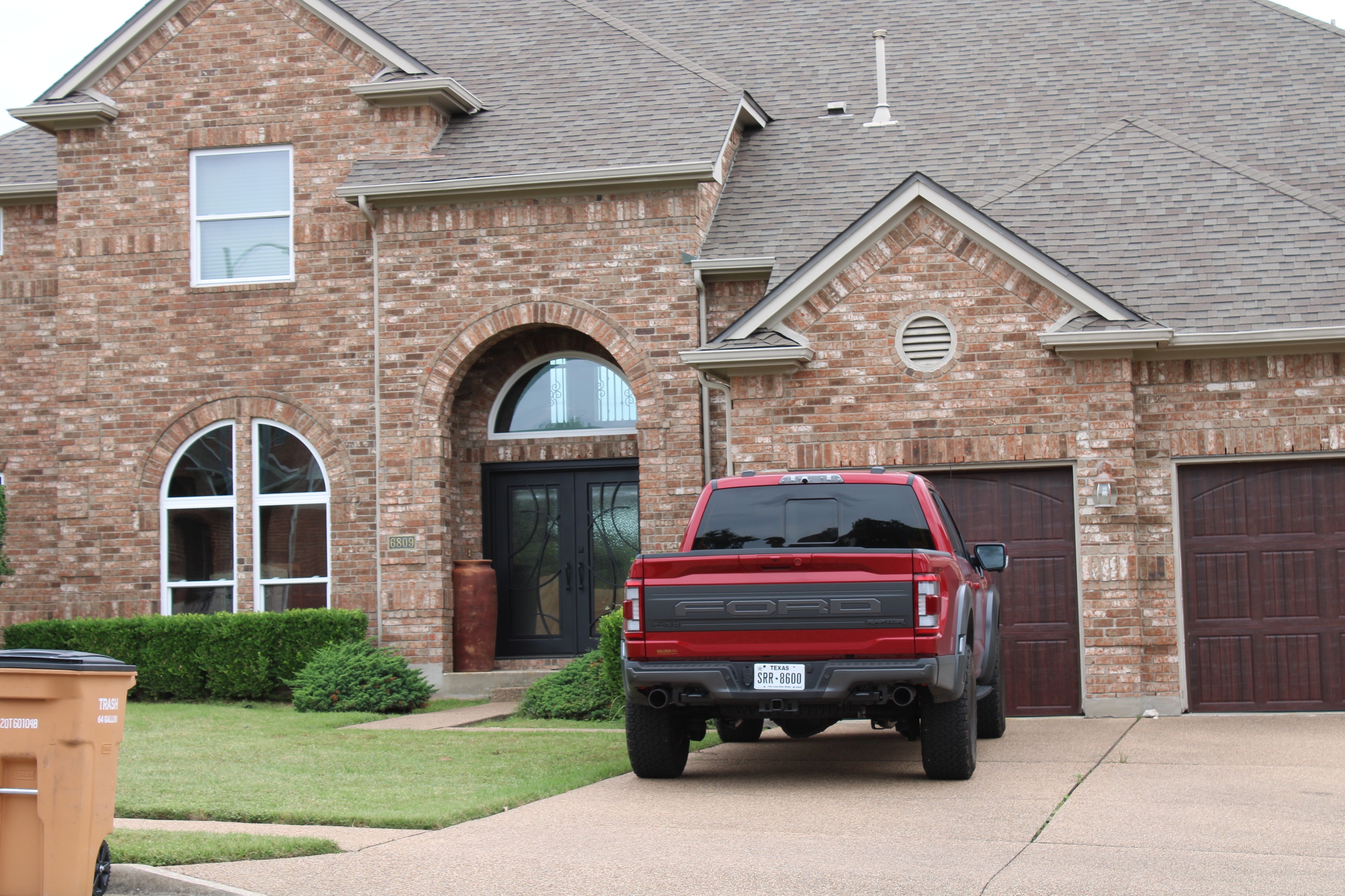 Brick exterior of Austin home with two-car garage, truck in driveway, and vinyl single-hung windows