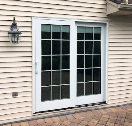 Exterior view of white sliding patio door with traditional grille pattern