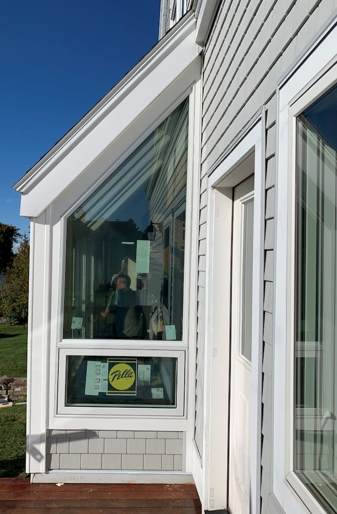 Exterior view of new wood windows with white trim on shingle-style home