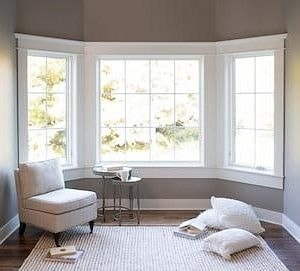 white chair in front of three windows forming a bay unit