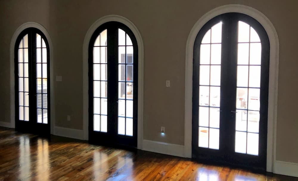 Interior view of three sets of arch-top wood French doors