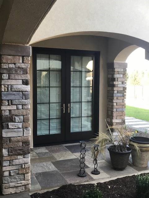 Exterior view of wood hinged French patio doors with traditional grille pattern