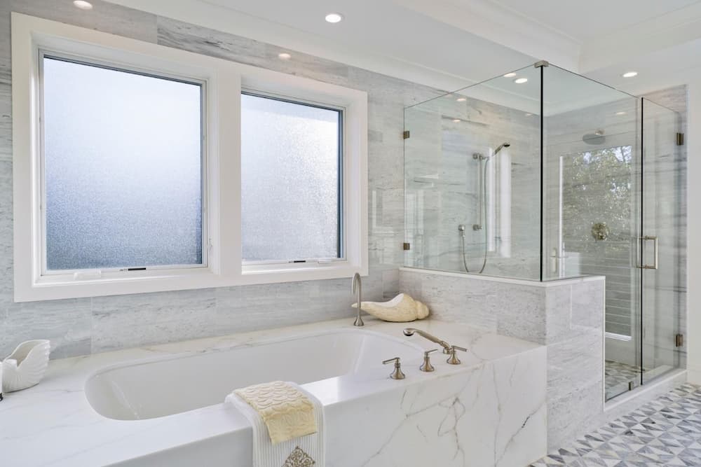 Two wood casement windows with frosted glass above a bathtub in a bathroom
