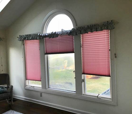 Interior view old of three old casement windows with pink blinds