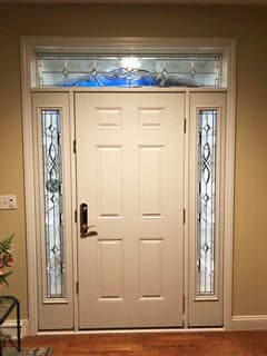 Interior view of white 6-panel fiberglass entry door with decorative glass sidelights and transom