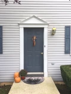Old blue-gray 6-panel entry door on home with white siding