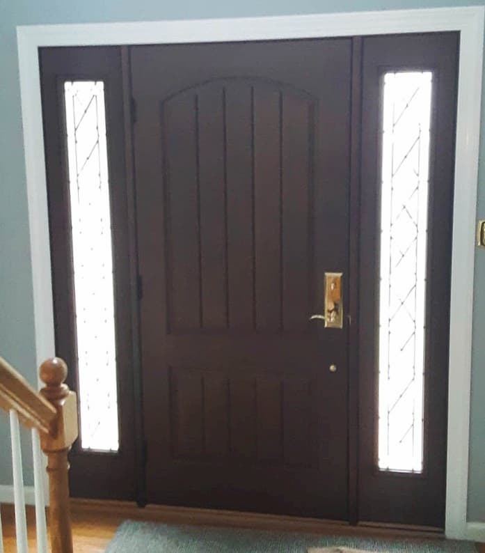 Interior view of new wood-grain fiberglass entry door with brass hardware