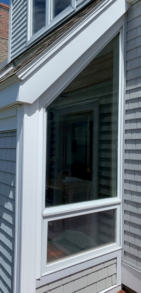 Exterior view of special shape and awning window on a shingle-style home