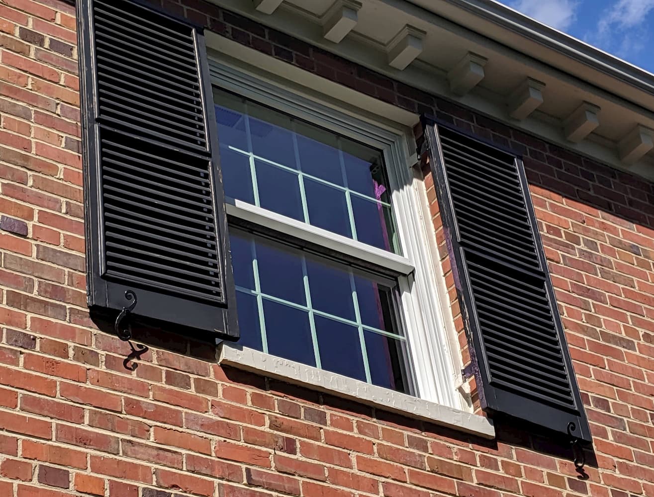 Wood double-hung window with traditional grille pattern on second story.