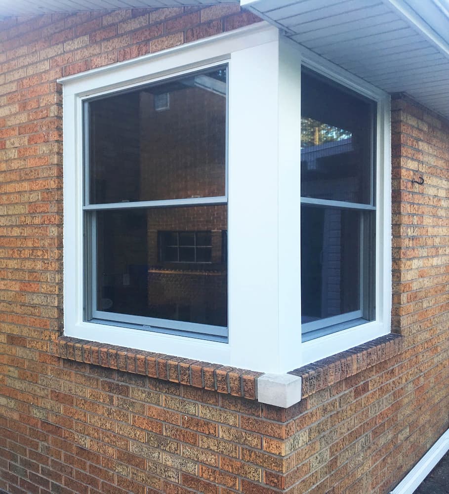 Exterior view of white double-hung windows on the corner of a home