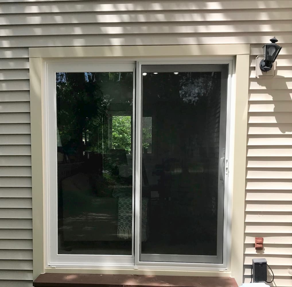 Exterior view of vinyl sliding patio door on home with beige siding