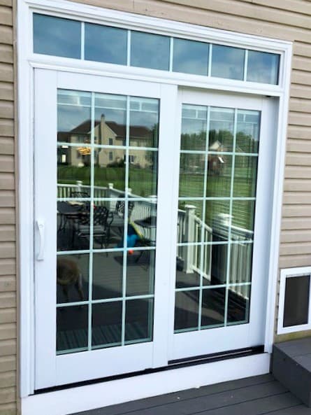 Exterior view of new white wood sliding patio door with transom.