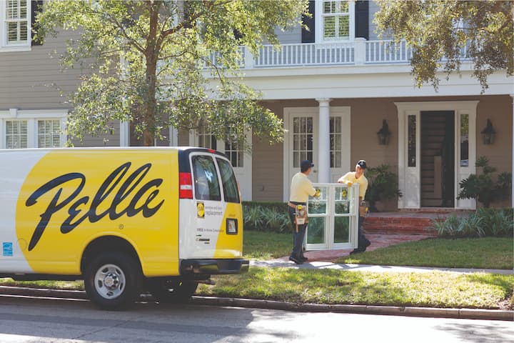Pella van parked in front of home with two men carrying replacement window