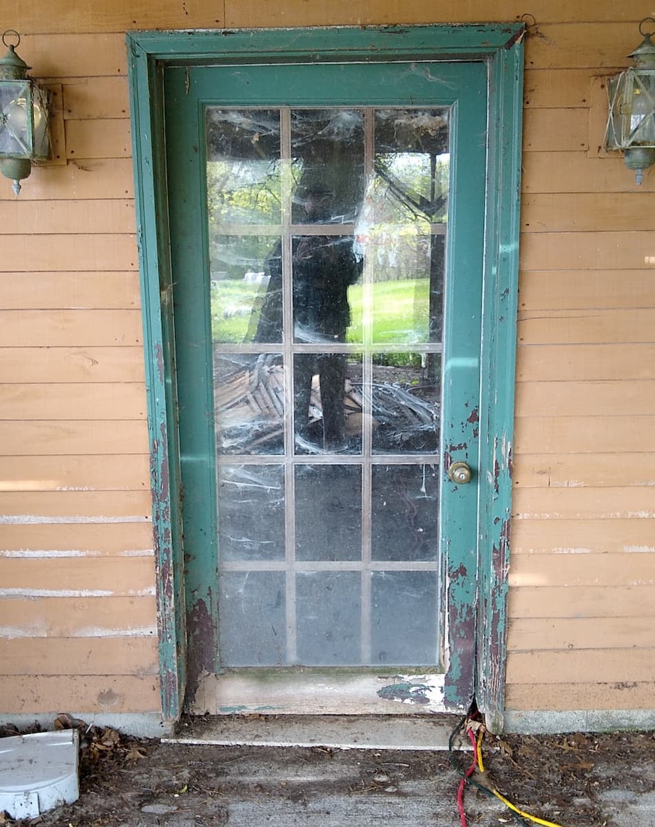 Exterior view of old, damaged basement door.