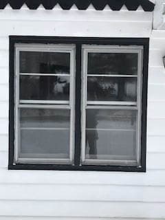 Exterior view of old double-hung windows against white siding