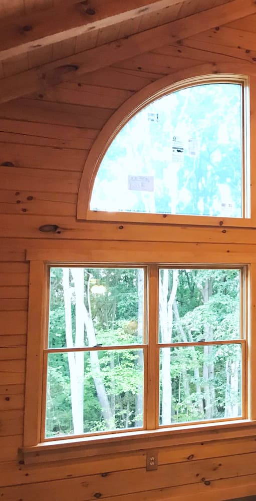 Interior view of log cabin with wood fixed special shape and double-hung windows