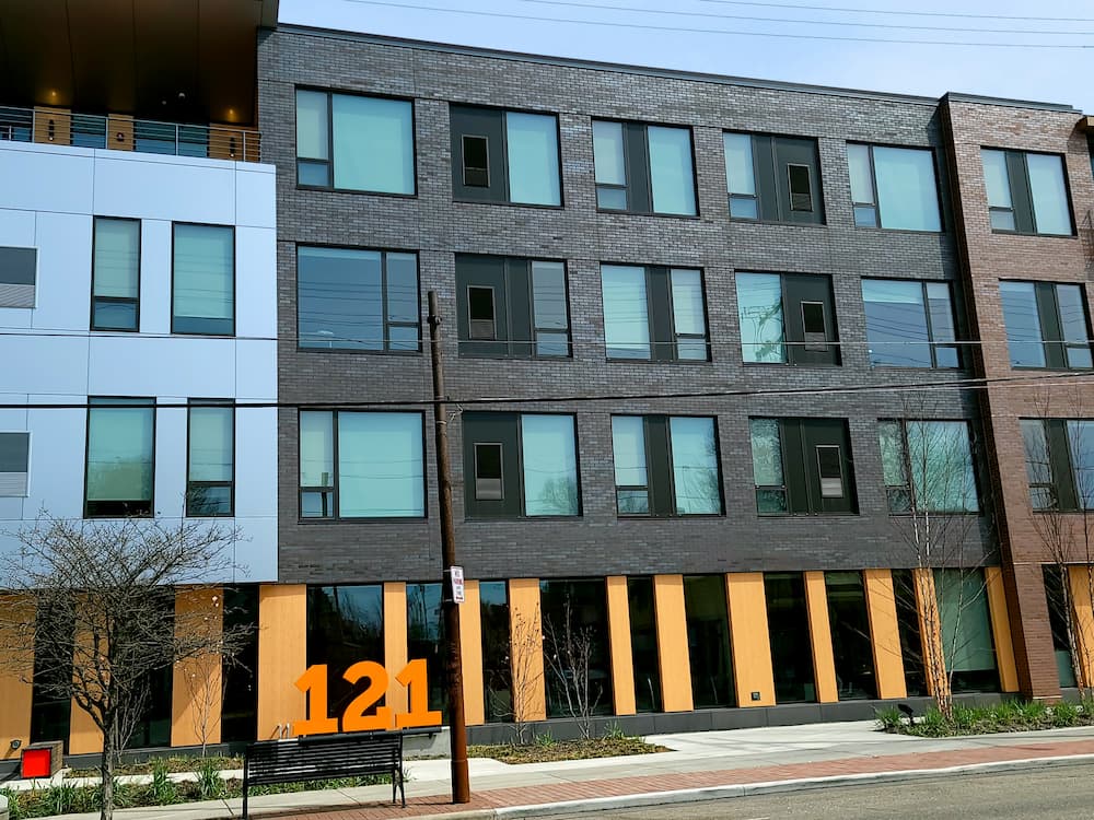 Street view of new apartments featuring orange accents and brown Pella fiberglass windows