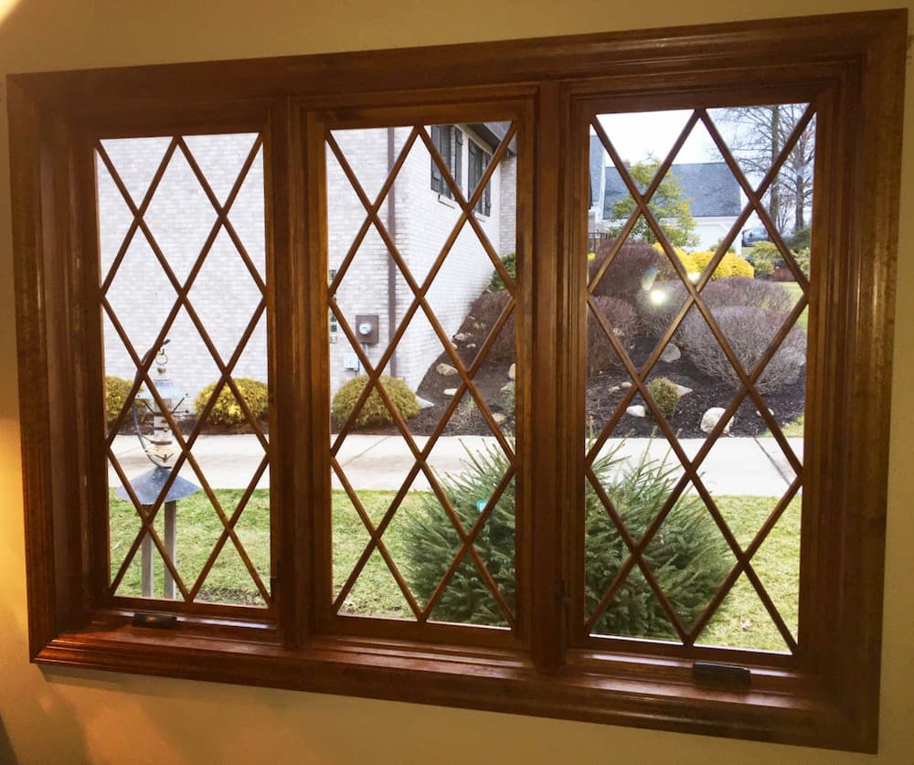 Interior view of three wood casement windows with diamond grille pattern
