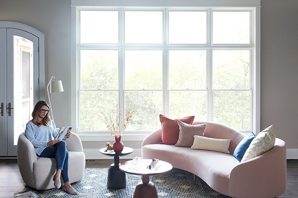 Woman reading a book in living room with Lifestyle Series windows reducing outside noise