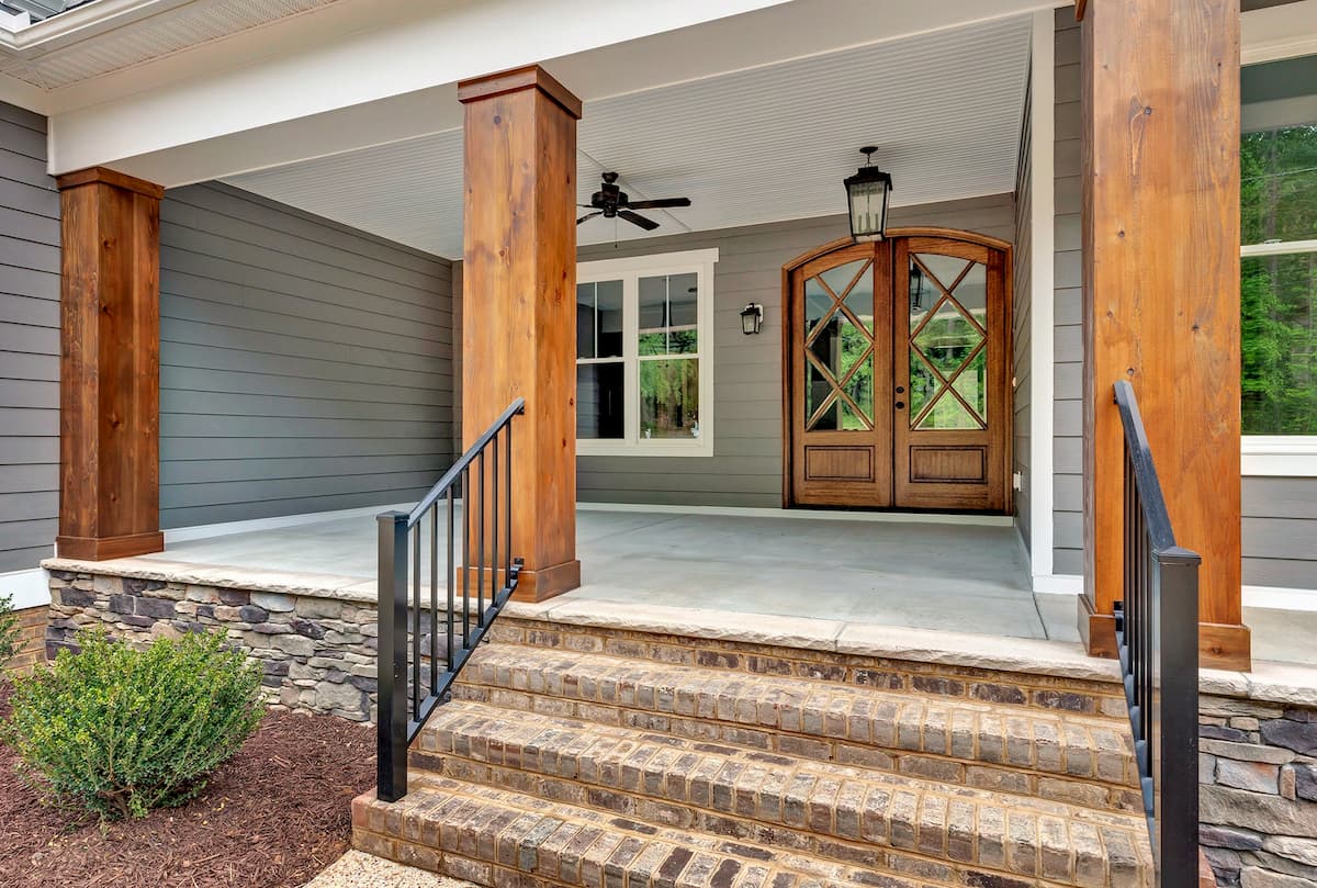 Covered front porch with wood double entry doors and white vinyl double-hung windows