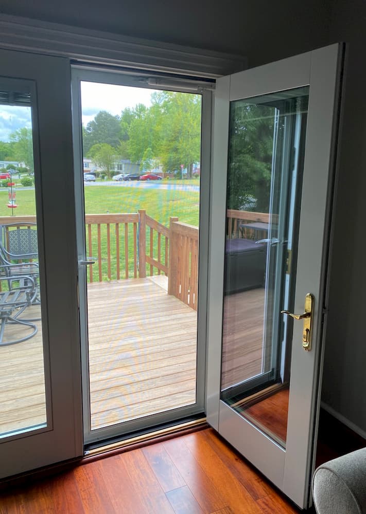Interior French door open to a hinged storm door leading to a balcony