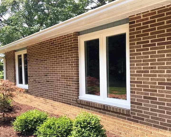 Exterior view of white replacement casement windows on brick home