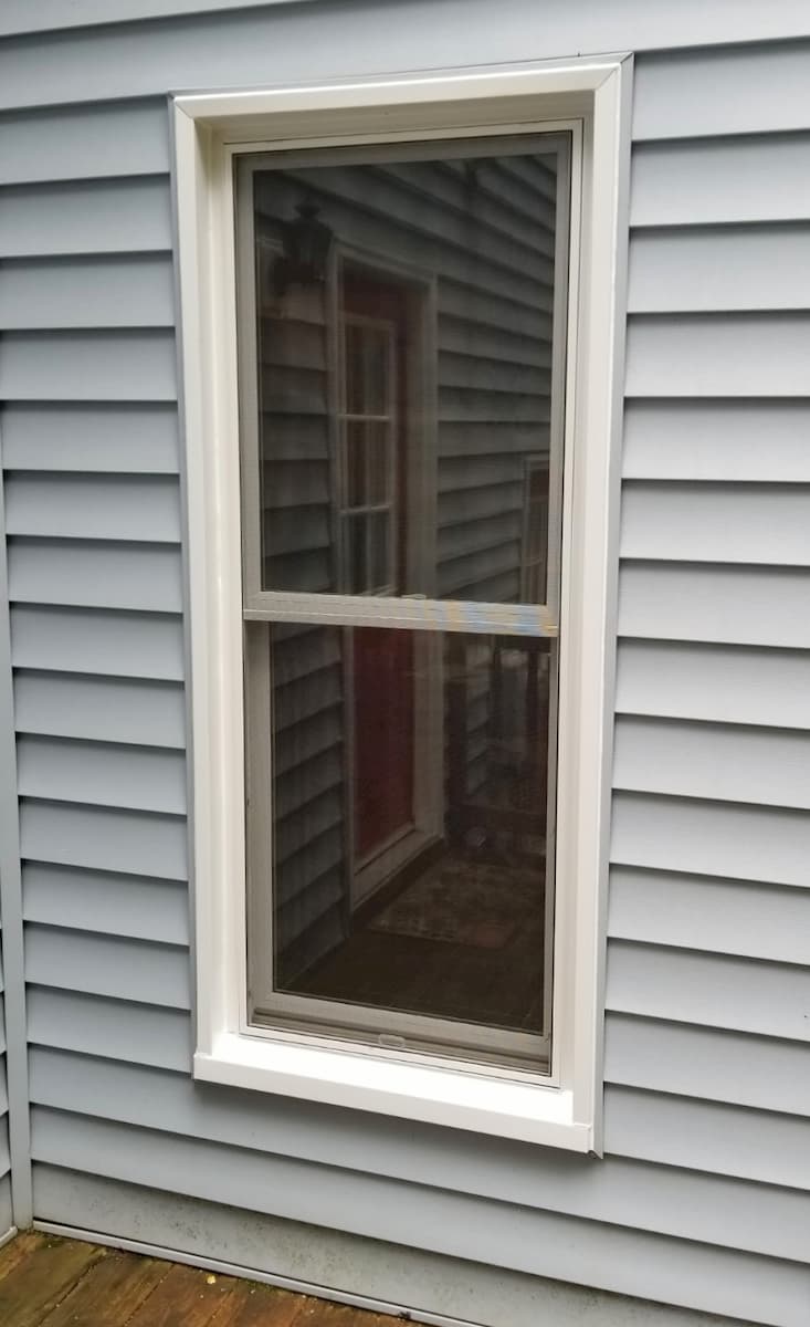 Exterior view of white fiberglass double-hung window on a home with gray siding
