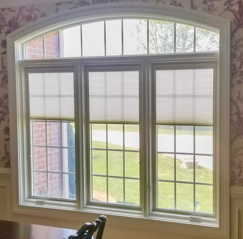 Three wood casement windows with traditional grille patterns topped with an arch window.