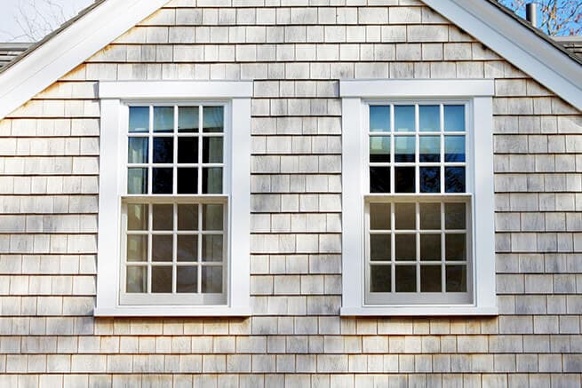 Exterior view of wood double-hung windows on a shingle-style home