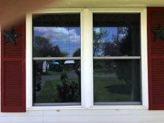 Old double-hung windows framed by red shutters