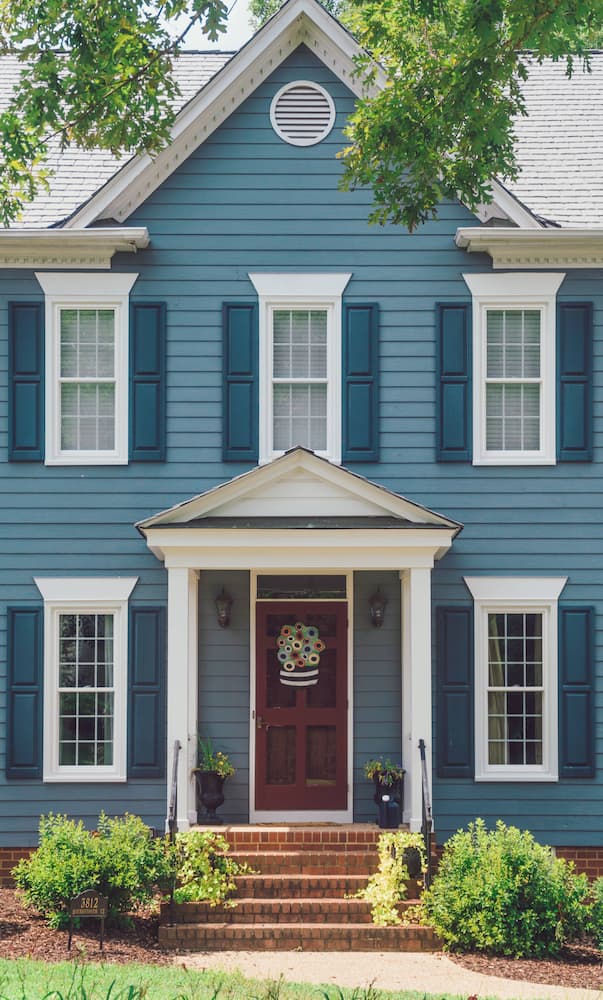 Blue home with white vinyl double-hung windows with traditional grille pattern