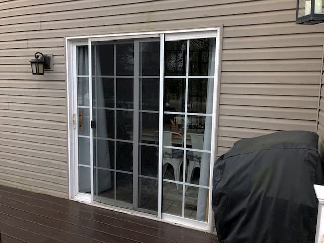 Exterior view of original sliding patio doors with white trim and grilles