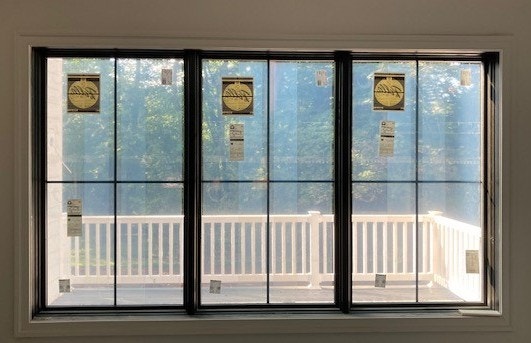 Interior view of three side-by-side black wood casement windows.