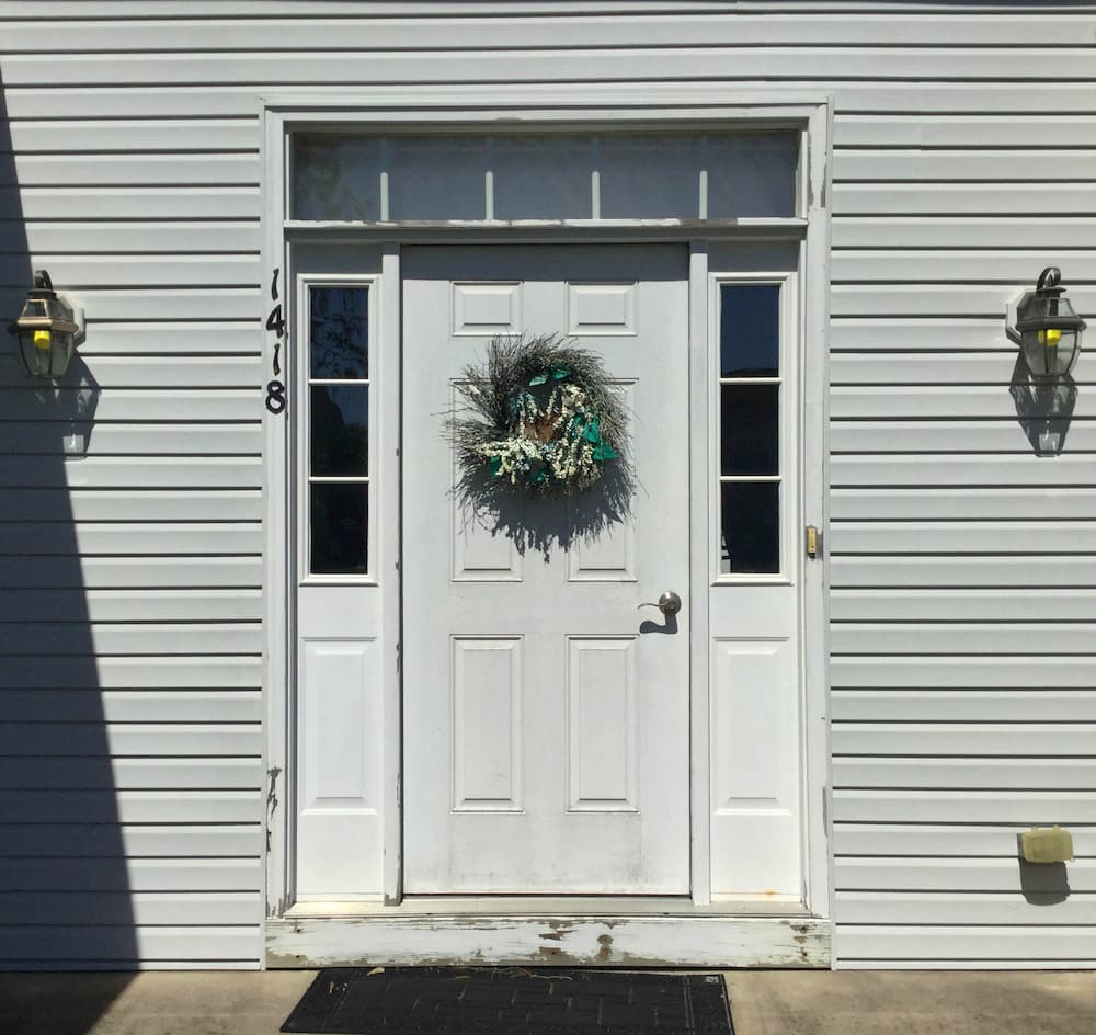 Exterior view of old white front entry door with sidelights and transom