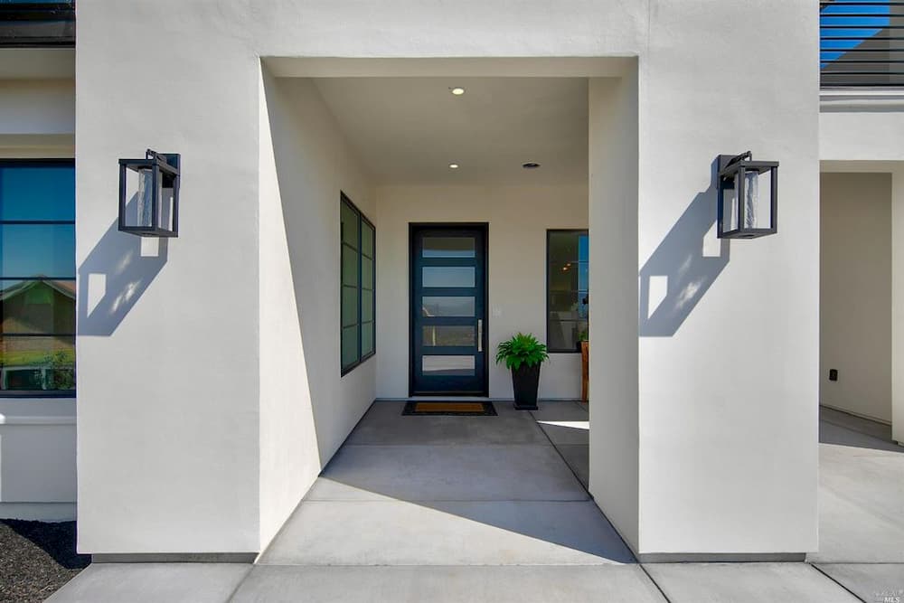 Exterior of home with contemporary black wood entry door and windows