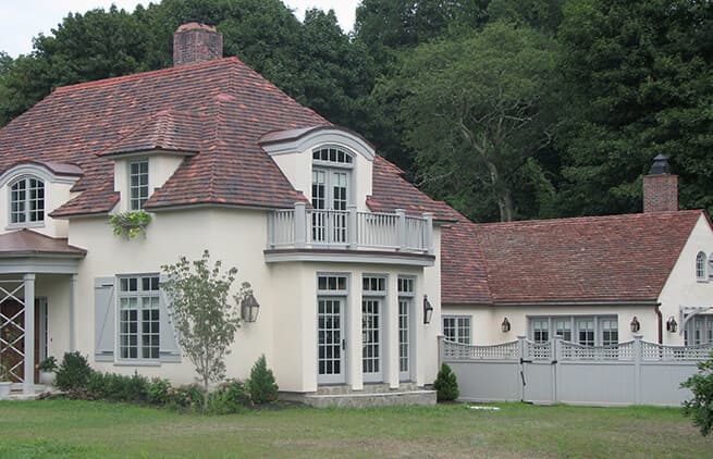 Exterior view of Provencal-style home with wood patio doors and windows