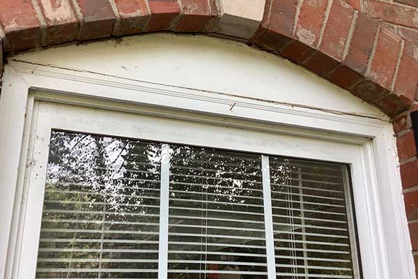 Close-up of white frame window with black shutters on brick Brentwood, TN, home