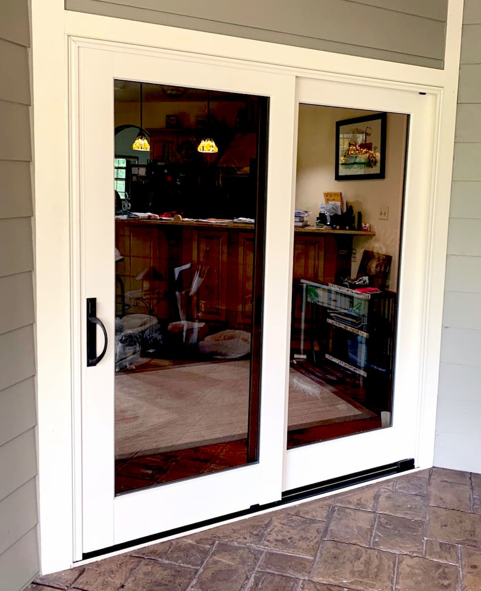 Exterior view of white wood sliding patio door with black handle.