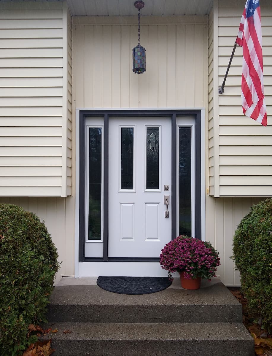 Exterior view of new white fiberglass entry door and vinyl window sidelights.