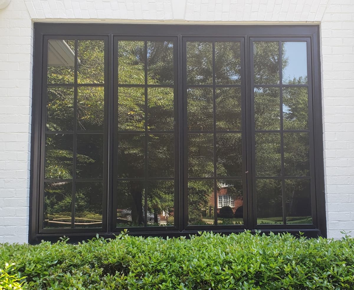 Four side-by-side black casement windows with traditional grille patterns