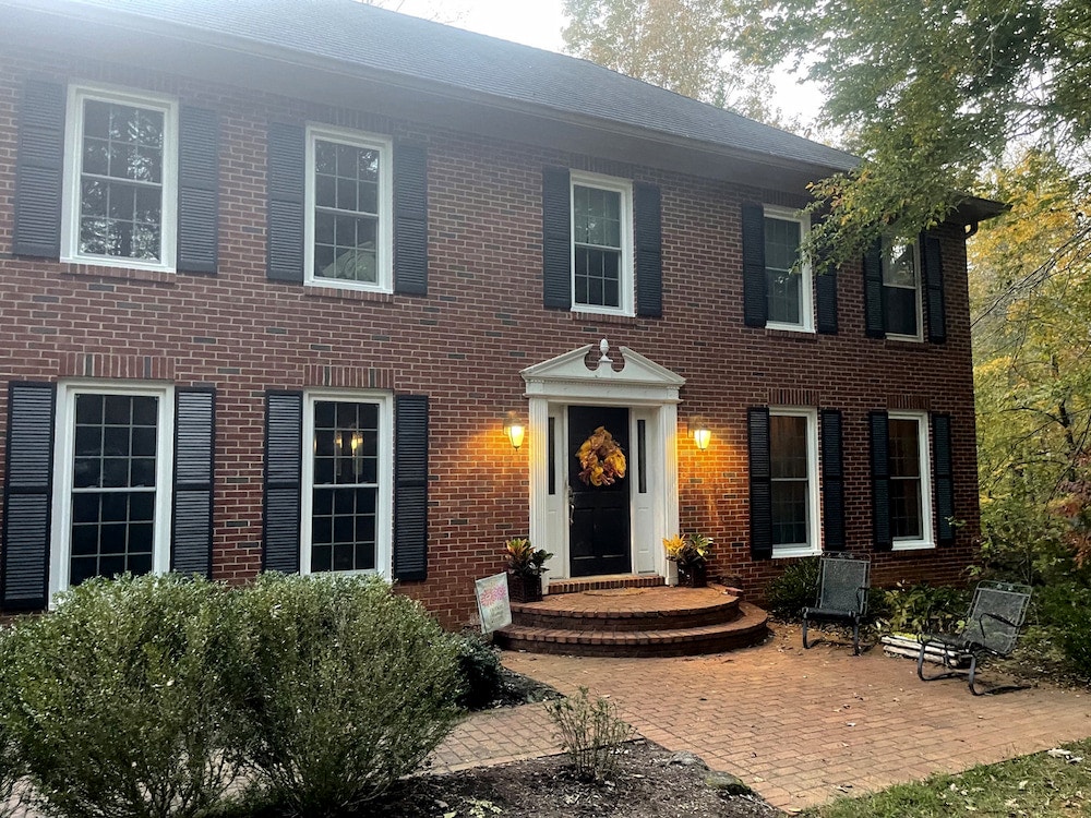 Brick exterior of two-story Charlottesville home with white double-hung windows and black shutters