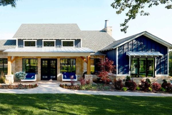 Exterior of blue home with white trim and established landscaping