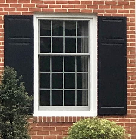 Exterior view of white wood double-hung window on a brick home