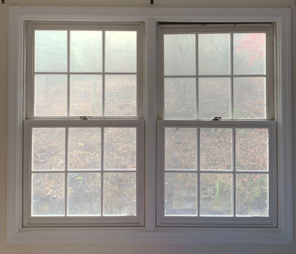 Interior view of old white double-hung windows with traditional grille pattern