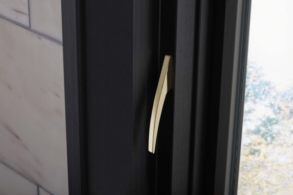 Modern brass sash lock on black casement window